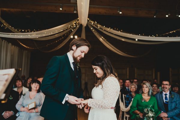 groom puts wedding ring on to his brides finger in the ceremony room as their guests look on, styal lodge wedding photography, styal lodge wedding photographer, manchester wedding photographer, manchester wedding photography, cheshire wedding photographer, cheshire wedding photography
