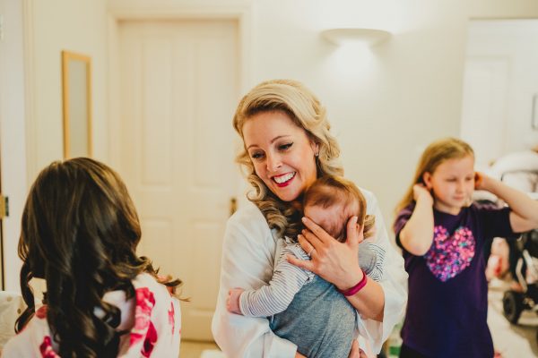 bride holds a baby and smiles at another girl