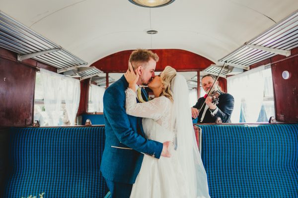 bride and groom kiss on the train with the violinist in the background, elsecar heritage centre wedding photographer, elsecar heritage centre wedding photography, elsecar heritage centre wedding, ayesha photographer, manchester wedding photographer, manchester wedding photography, sheffield wedding photographer, sheffield wedding photography, barnsley wedding photographer, innercity weddings